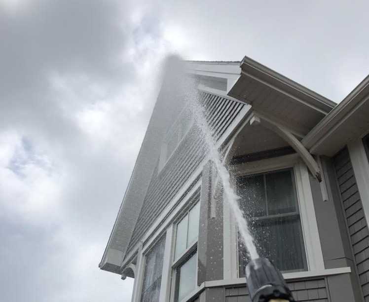 Three story victorian house being pressure washed.