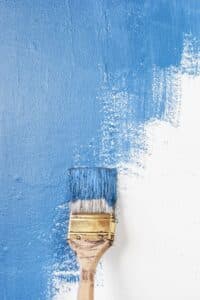 Picture of a paintbrush painting a wall blue.